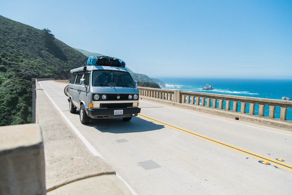 van crossing bridge over body of water