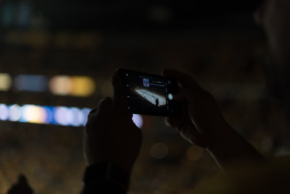 person holding phone filming game