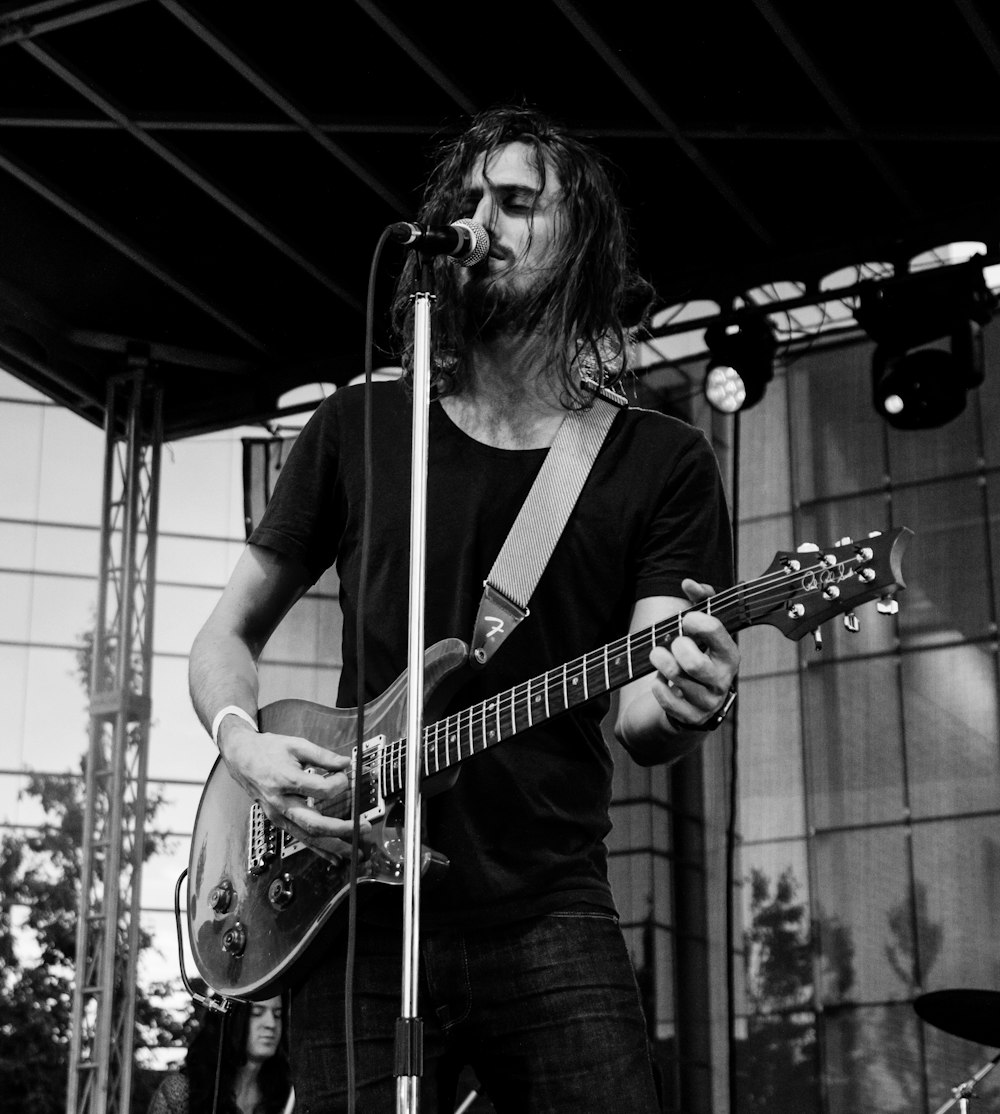 grayscale photography of man holding guitar