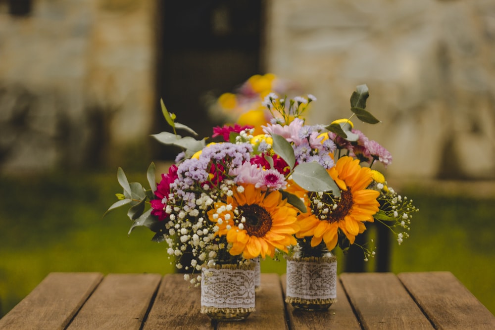 two bouquet of petaled flowers on brown wooden table