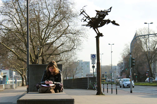 Young woman sitting in a park, jotting down notes about investing in government schemes.