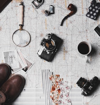 camera, pair of brown shoes, white ceramic mug, grey and black pen, brown smoking pipe