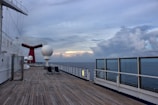 A cozy deck on a cruise ship with passengers sipping drinks and watching the horizon.