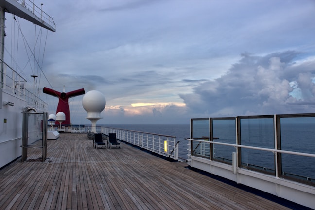 A cozy deck on a cruise ship with passengers sipping drinks and watching the horizon.
