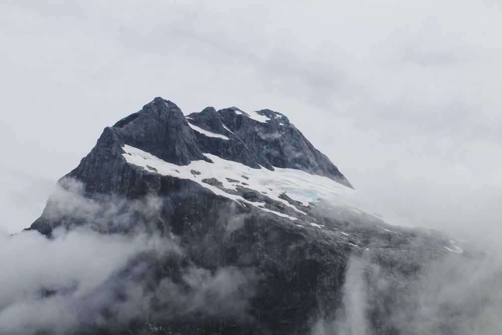 neve no topo da montanha cercada por nuvens