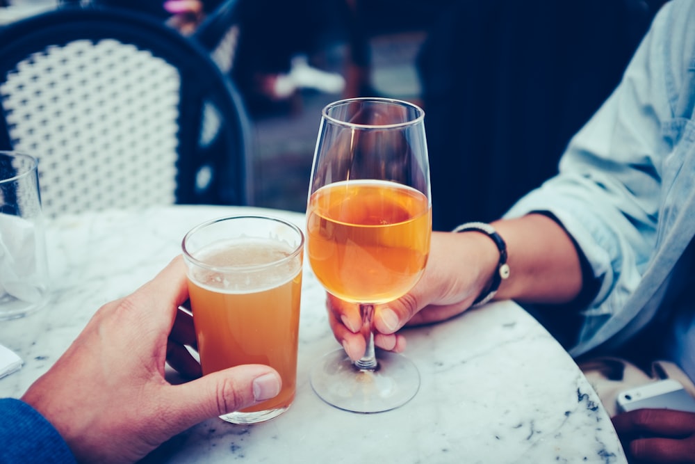 person holding goblet glass and highball glass