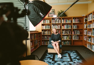 woman sitting on armless chair with light between bookcases in room