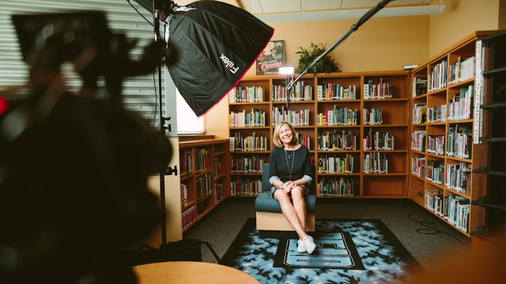 woman sitting on armless chair with light between bookcases in room