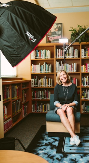 woman sitting on armless chair with light between bookcases in room