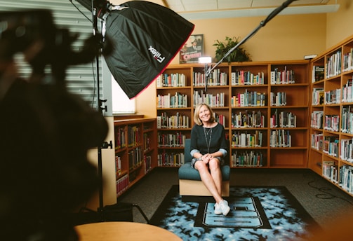 woman sitting on armless chair with light between bookcases in room