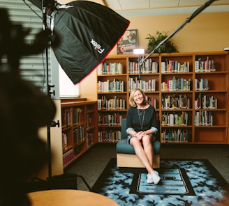 woman sitting on armless chair with light between bookcases in room