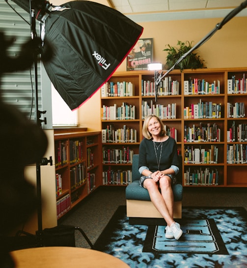 woman sitting on armless chair with light between bookcases in room