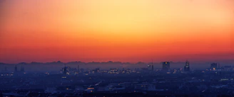 A panoramic view of Calgary's skyline blending into a vibrant Los Angeles cityscape at sunset.