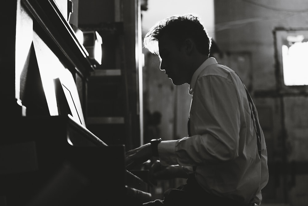 grayscale photography man playing piano