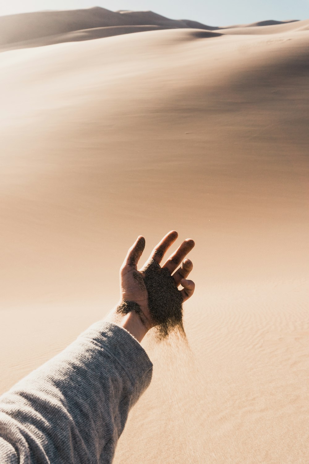 Person, die während des Tages Sand aus der Hand fallen lässt