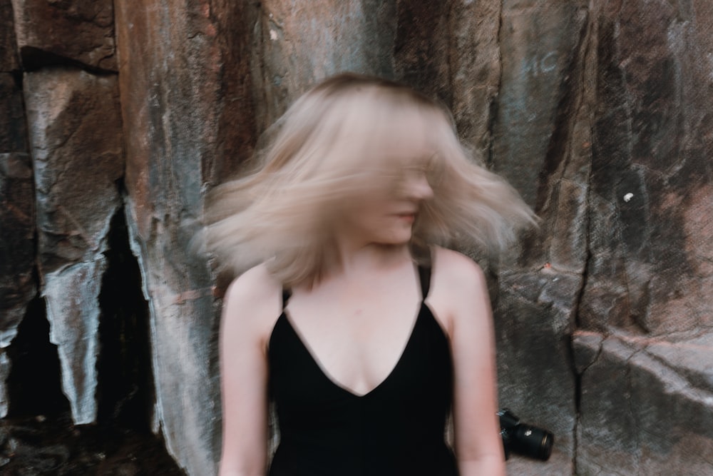 a woman with blonde hair standing in front of a rock wall