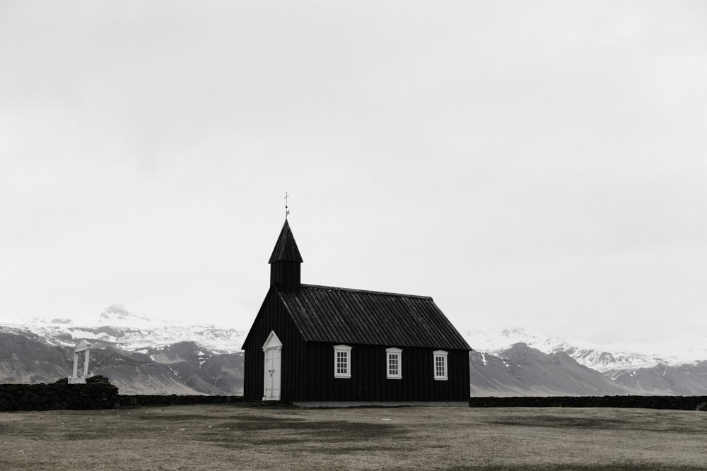 Une petite chapelle dans une plaine avec des montagnes enneigées à l’horizon