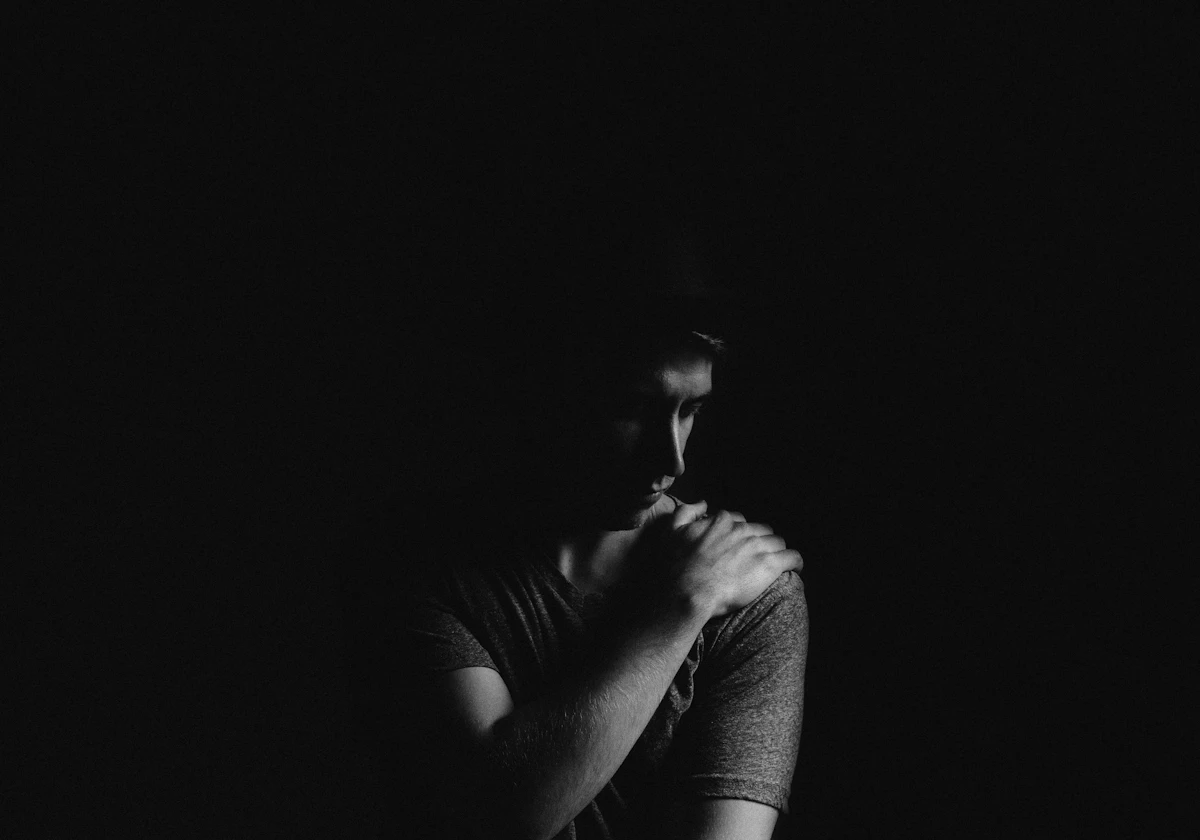 Man holding his shoulder in pain, a common presentation of frozen shoulder
