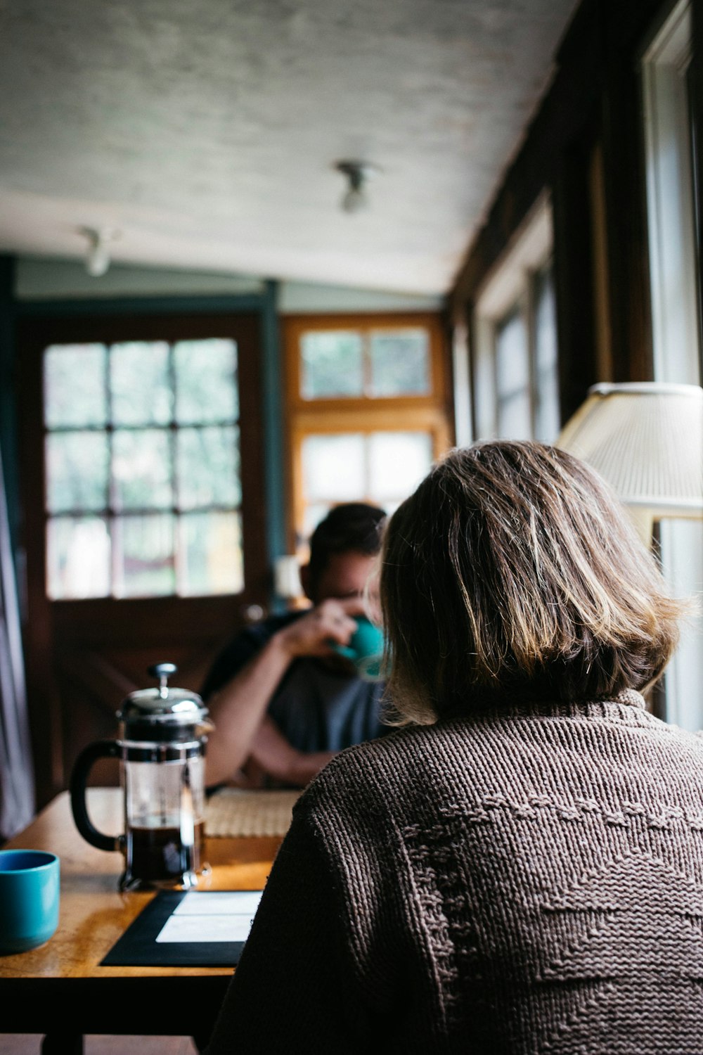 Person, die vor dem Tisch mit Kaffeepresse sitzt