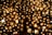 A multitude of glowing circular lamps are clustered together, creating a warm, golden ambiance. The lamps are arranged in a dense pattern with a lattice-like structure running vertically through the center. The light emitted is soft and diffused, casting a serene glow across the scene.