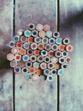 A vibrant collection of colored pencils arranged in a fan shape on a rustic wooden table.