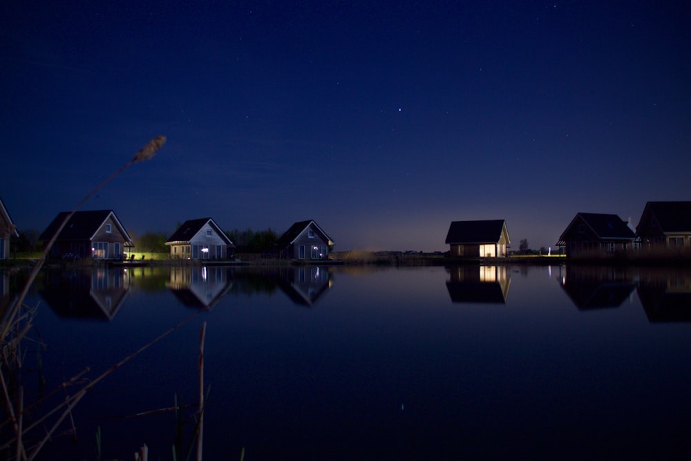 夜の6軒の家や木々の近くの穏やかな水域