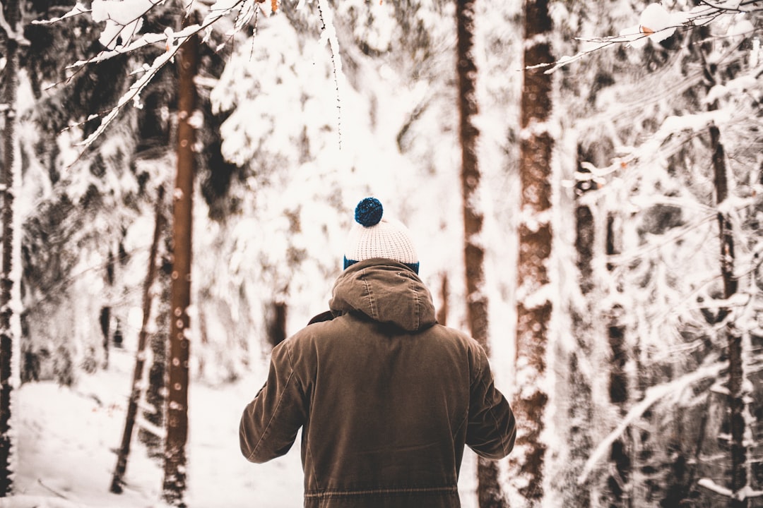 person standing in middle of trees covered in snow