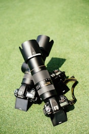 two black Nikon DSLR cameras on green grass
