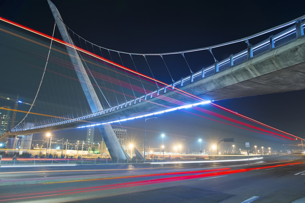 Fotografía de lapso de tiempo de vehículos debajo de un puente de concreto durante la noche