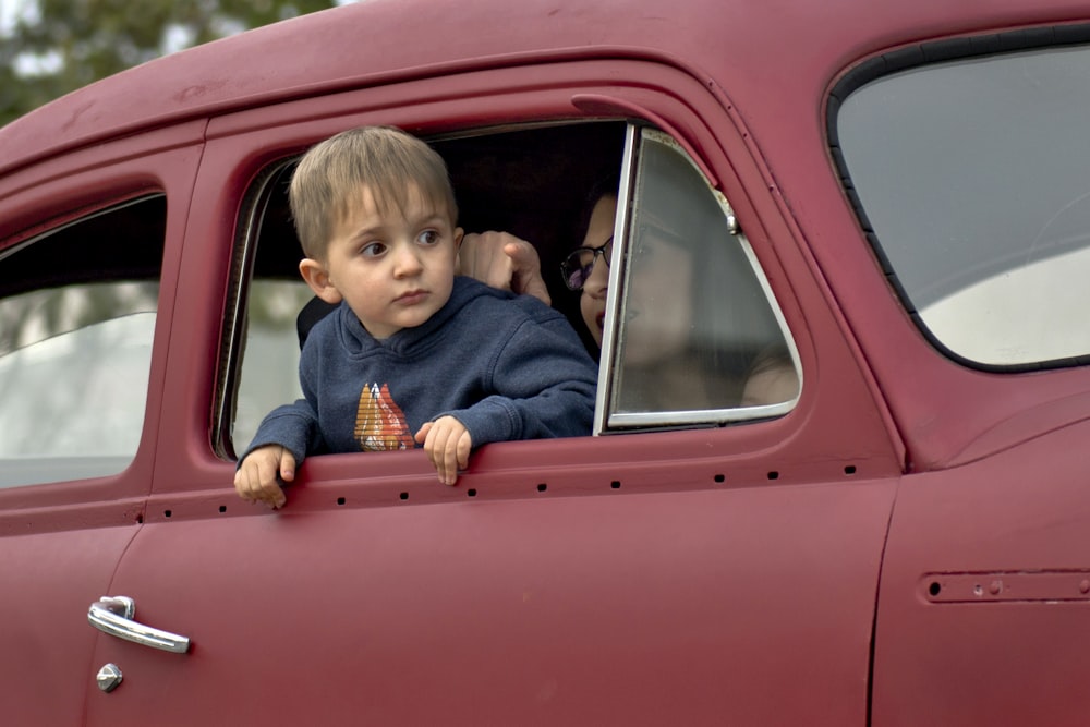 toddler riding on red vehicle