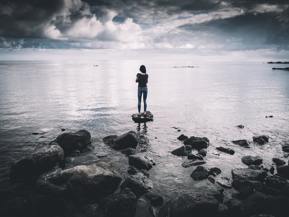 woman standing on rock surrounded with body of water