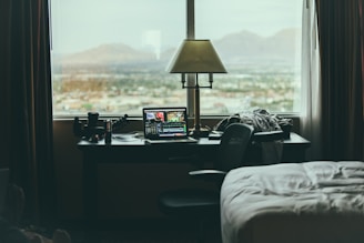 tabletop lamp beside laptop on desk beside window