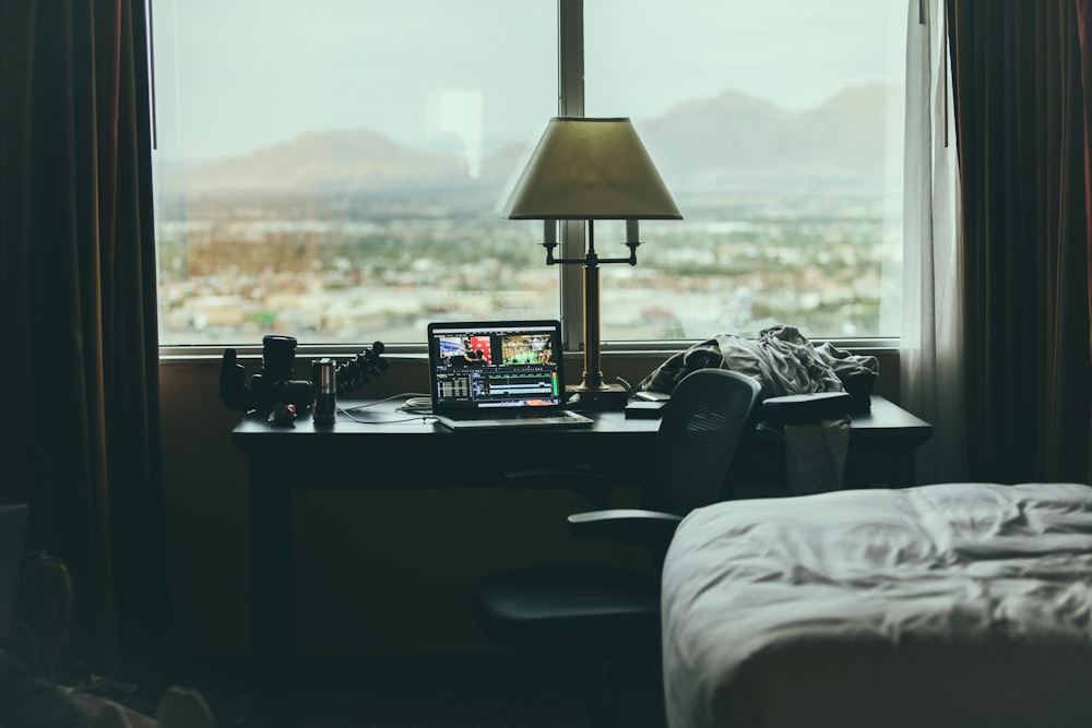 tabletop lamp beside laptop on desk beside window