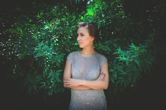 A serene, minimalist photo of a woman wearing an elegant olive green dress, standing in soft natural light.
