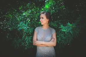 An elegant woman wearing a flowing Lumina Atelier dress in a sunlit urban courtyard.