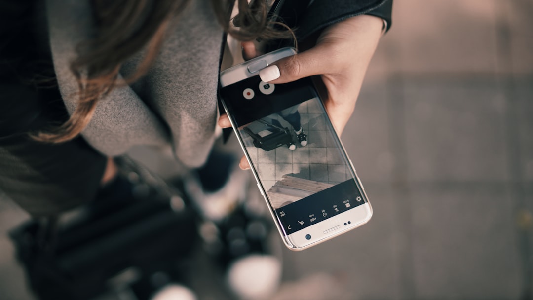 A woman with a suitcase holding a Samsung phone with its camera pointed at her feet