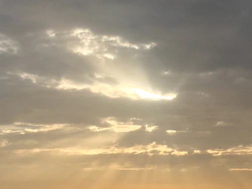 A heavenly pathway through clouds with golden rays shining down, symbolizing Chacko’s arrival in the family’s celestial reunion.