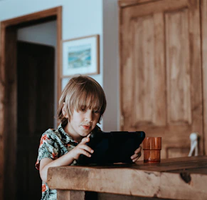 A cheerful toddler watching a playful educational video on a tablet with Boo Bear characters.