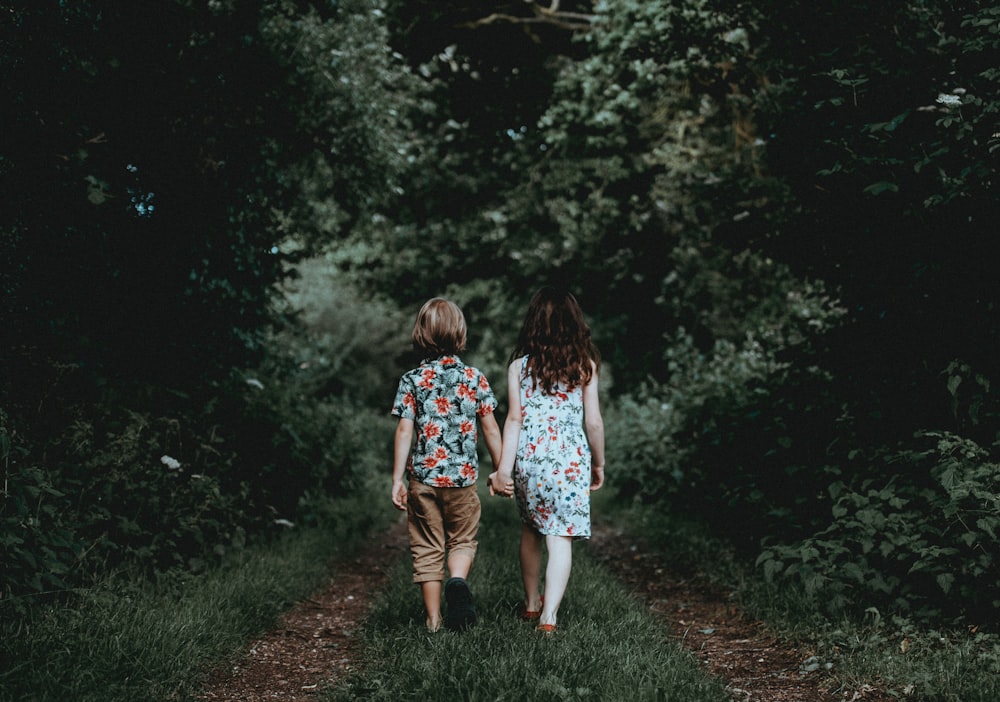 ragazzo e ragazza che camminano mano nella mano verso il bosco