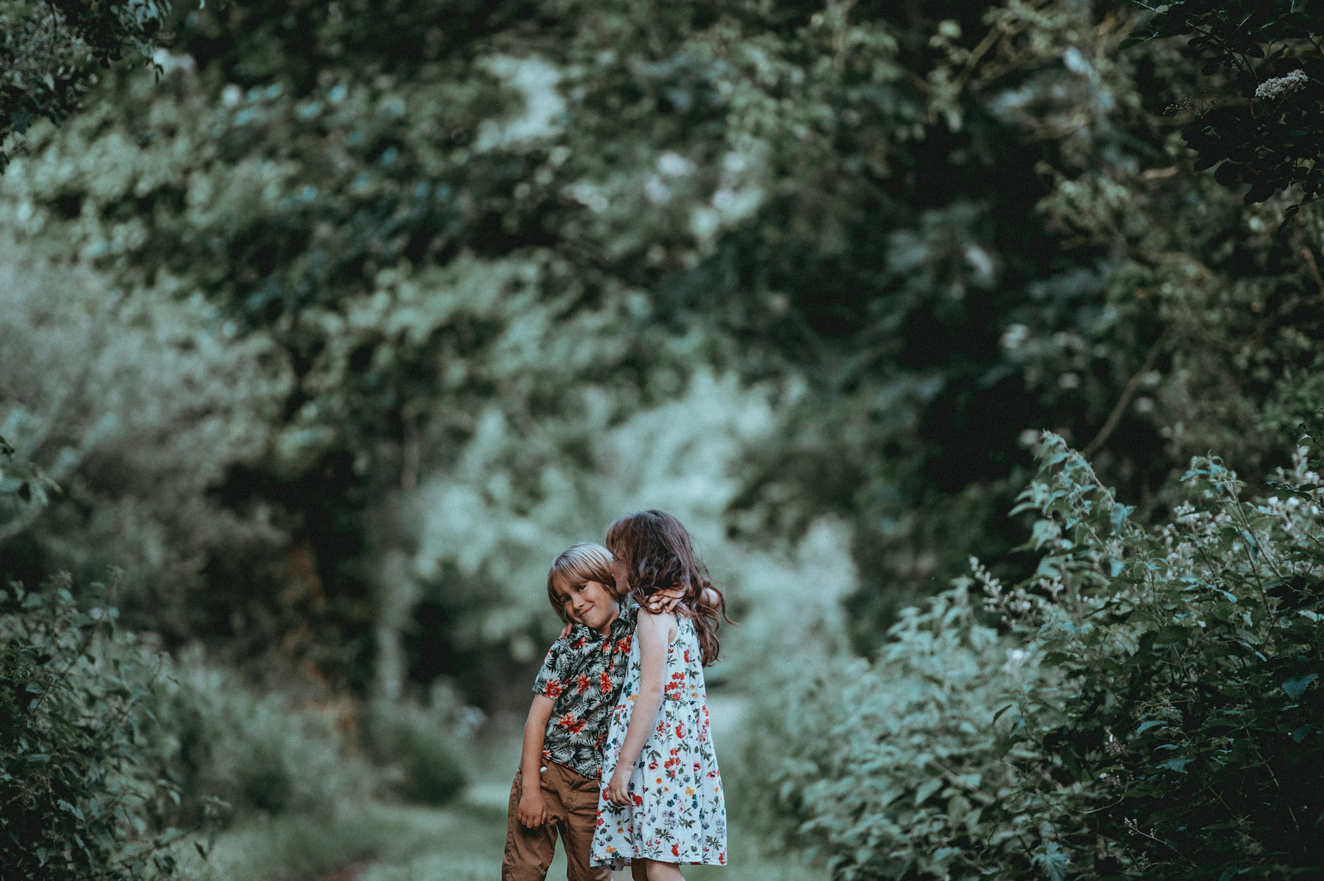 Two children hugging on a forest trail