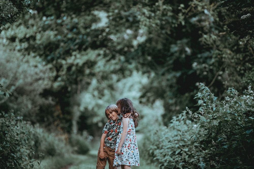 boy and girl standing in middle of forest trail