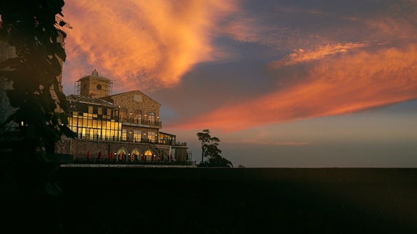 A panoramic shot of a completed masonry building standing proudly against a sunset.