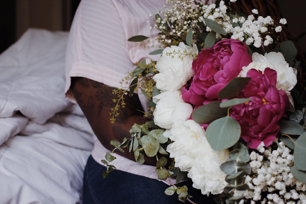 a person holding a bouquet of flowers on a bed