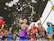 A lively group of kids dancing around a foam cannon with music playing in the background.
