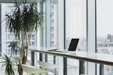 inside a corporate office with clean, floor to ceiling windows with a view of corporate buildings