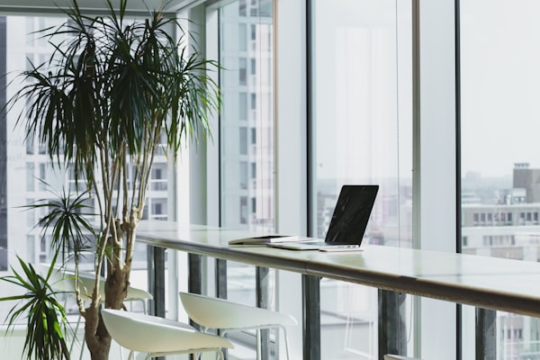 Stock image of a laptop sitting on a bench in a corporate office overlooking a city