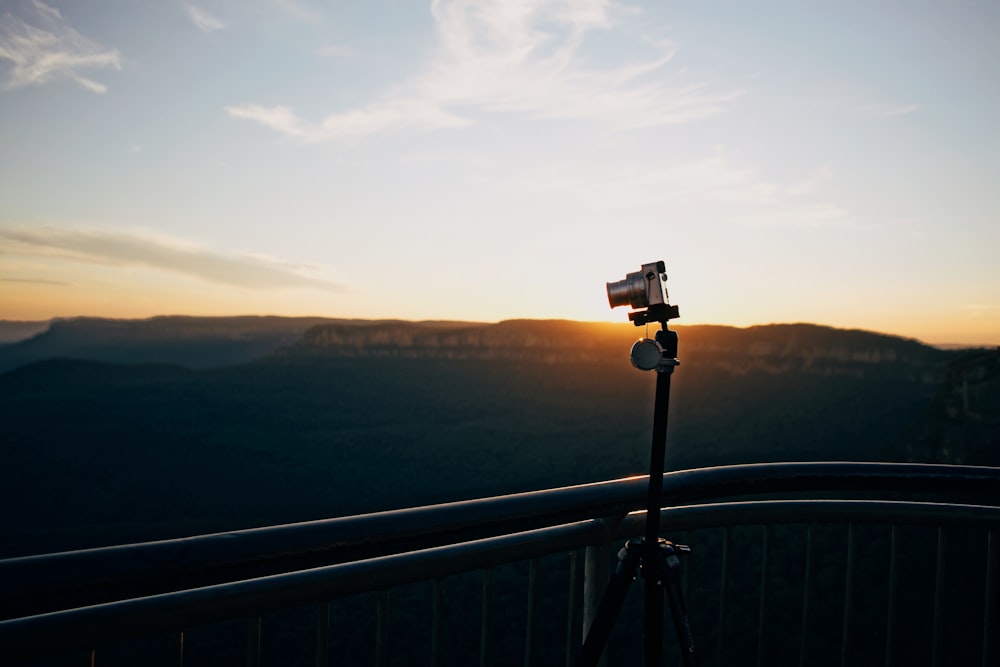 gray DSLR camera on tripod near railing