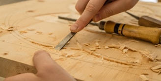 person using chisel while curving wood