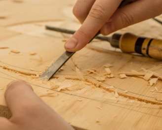 person using chisel while curving wood