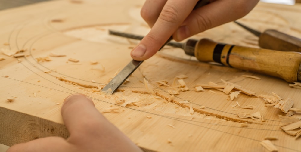 person using chisel while curving wood